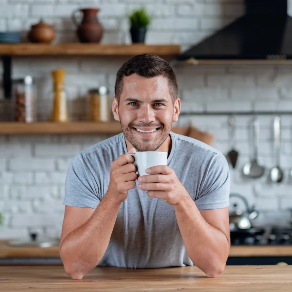 man smiling after teeth whitening holding a cup of coffee